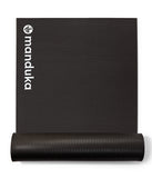 Manduka ENDURA 10mm siyah egzersiz matı, rulo halinde ve Manduka logosu görünür.