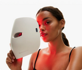TheraFace Mask Glo cihazını elinde tutan kadın. Kırmızı ışık teknolojisi cilt tonunu eşitler, sıkılık sağlar ve ince çizgileri azaltır.