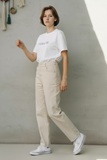 Namaste Oversize T-shirt beyaz, unisex oversize kesim; model bej pantolon ve beyaz spor ayakkabılarla.