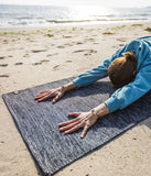 Sahilde Manduka Shala Yoga Rug / Black Heather ile yoga yapan birinin rahat anı. Sürdürülebilir el yapımı paspas.